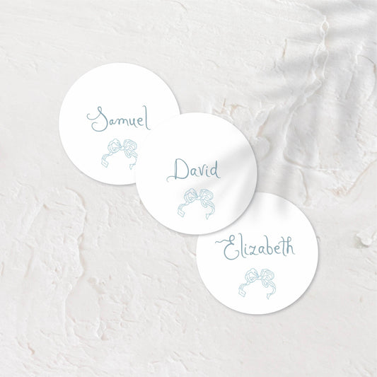White round place cards with blue tones and simple, elegant text.