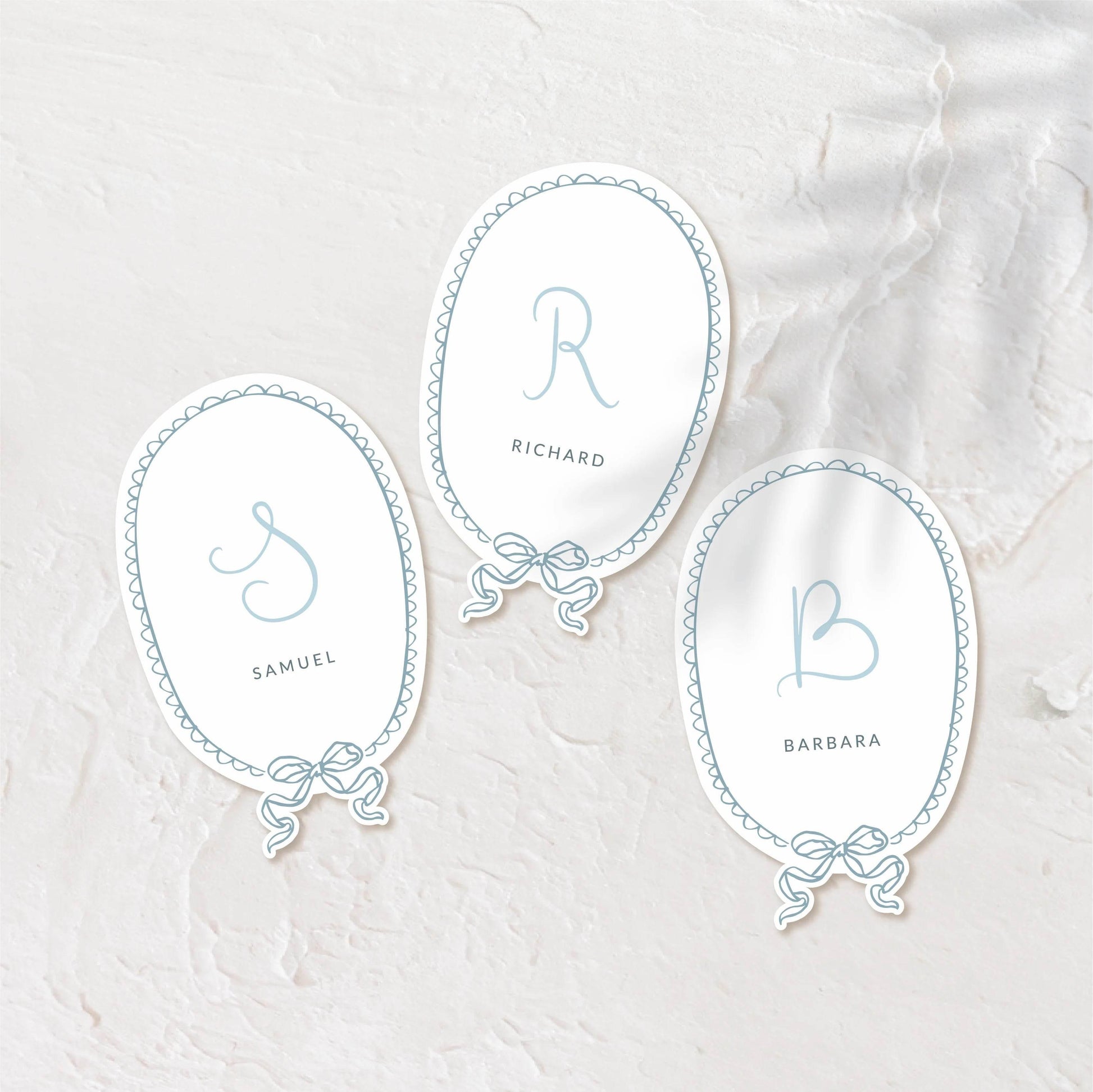 Oval place cards with delicate script and soft pastel background.