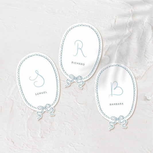 Oval place cards with delicate script and soft pastel background.