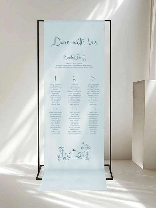 Contemporary fabric wedding seating chart with “Dine with Us” heading, featuring a minimalist design and soft blue tones in natural light.