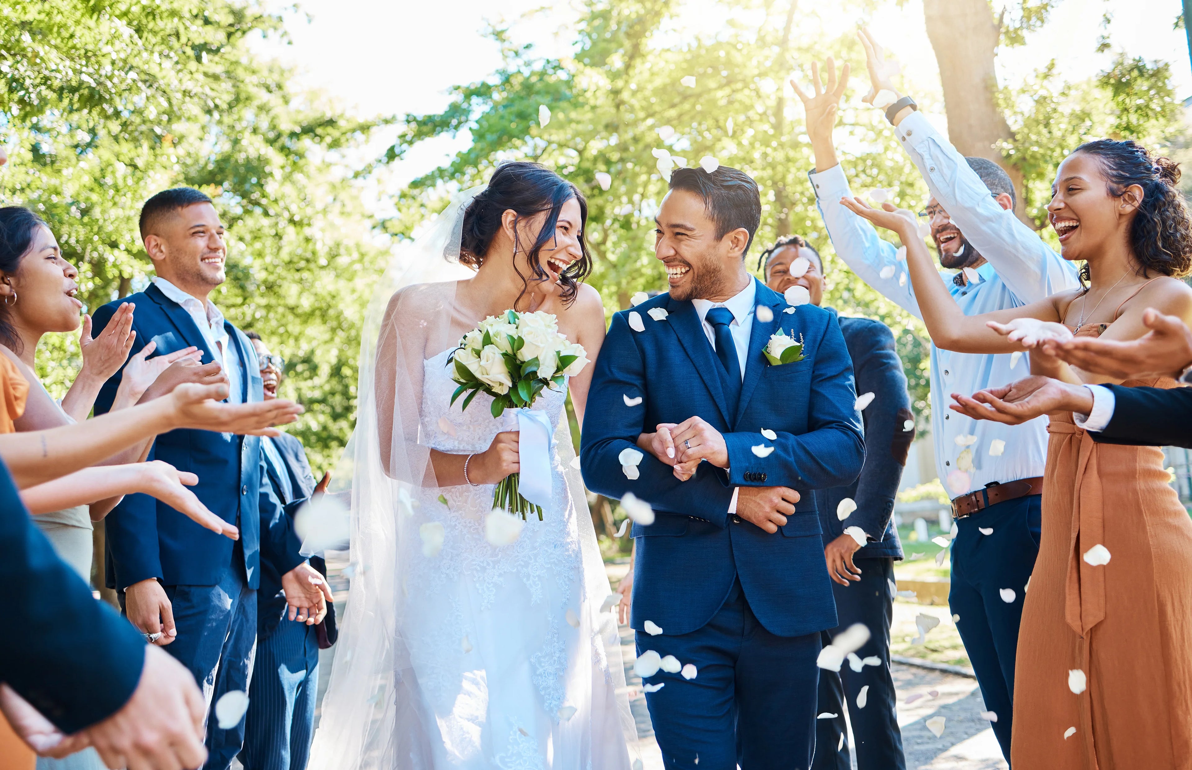 Wedding couple surrounded by guests with confetti in an outdoor setting