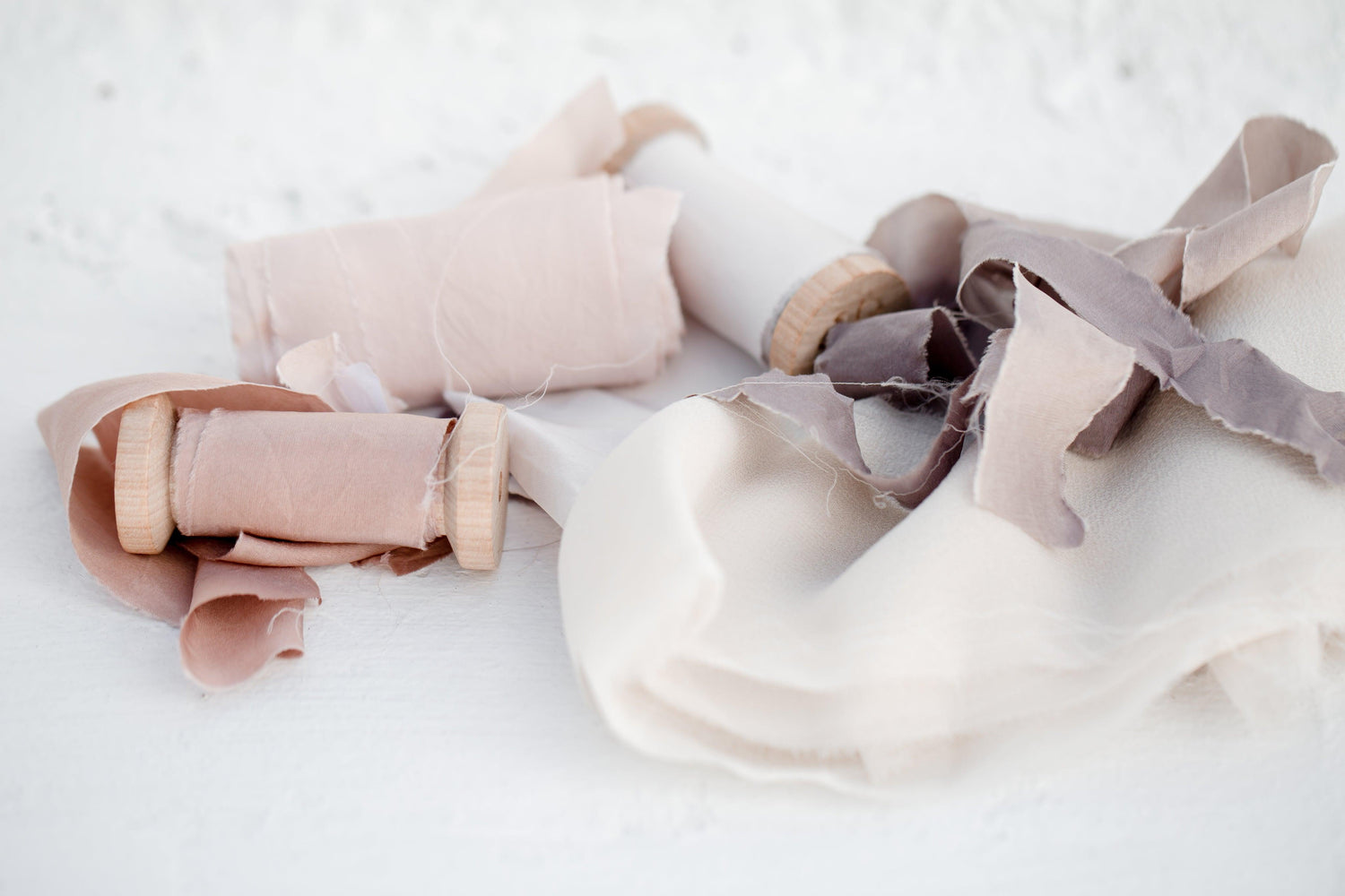 Three colored spools of silk ribbon with row edges