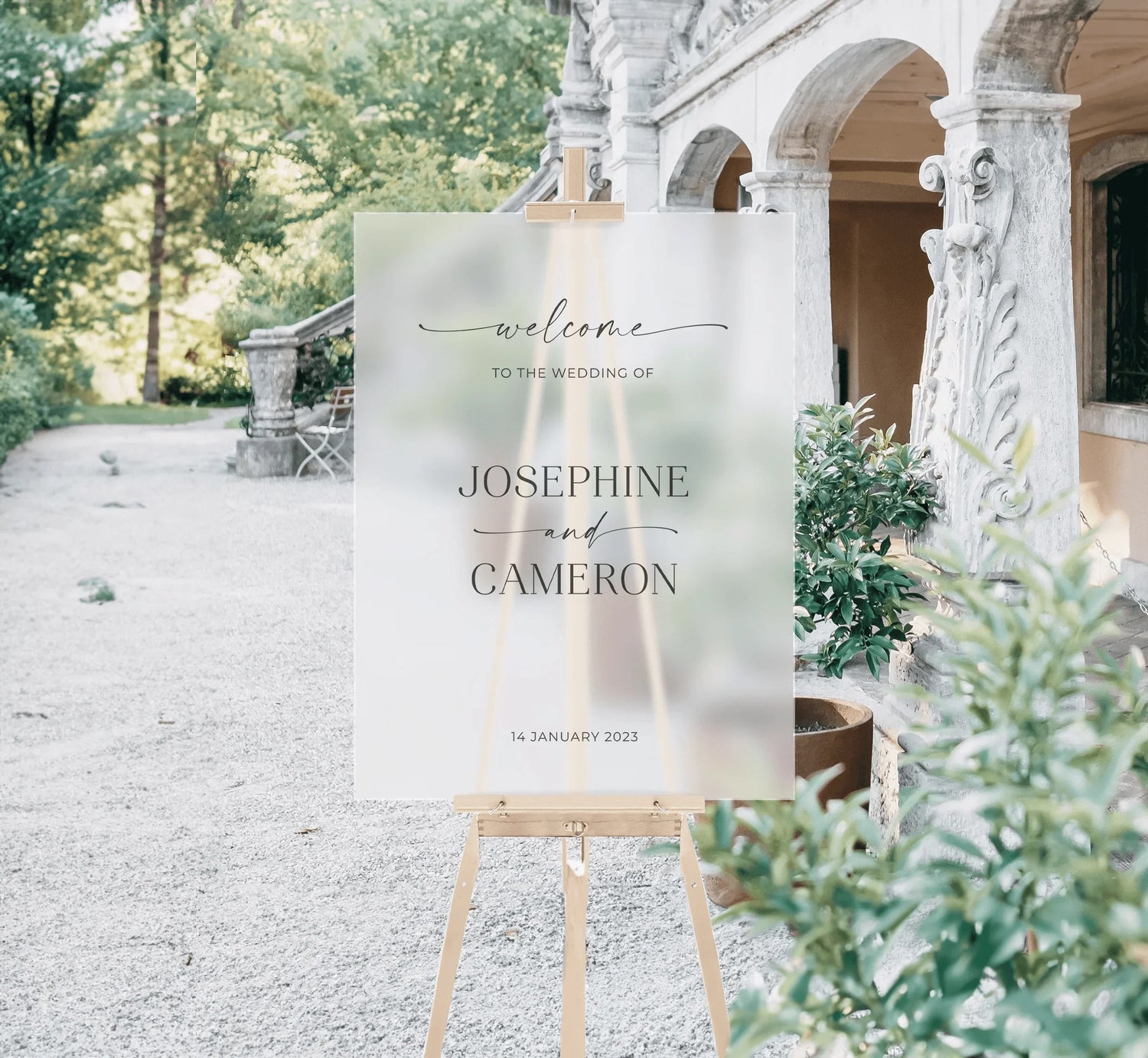 Sophisticated acrylic wedding welcome sign for Josephine and Cameron, displayed on a wooden easel against a garden setting.