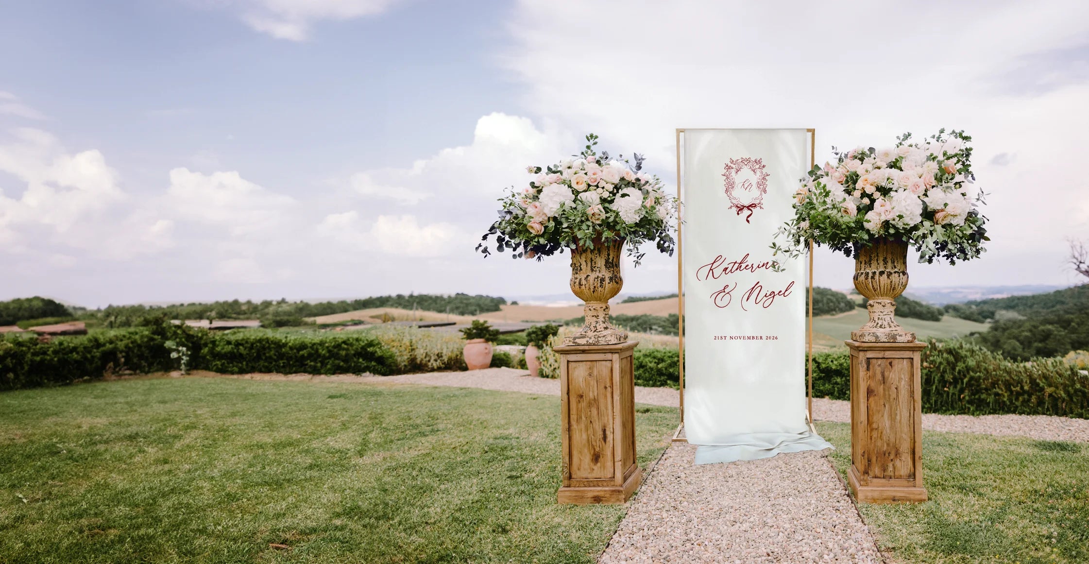 Decorative arch with floral arrangements and a wedding fabric sign in an outdoor setting.
